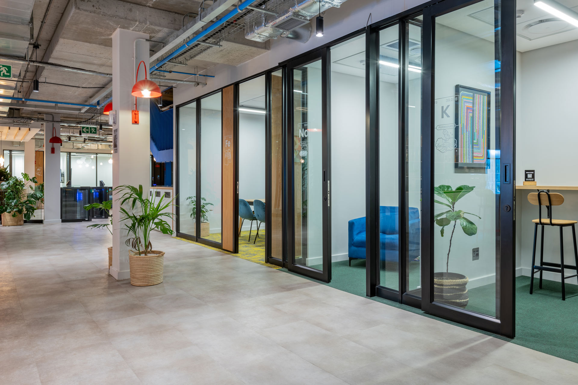 A number of office cubicles with glass screens and planters