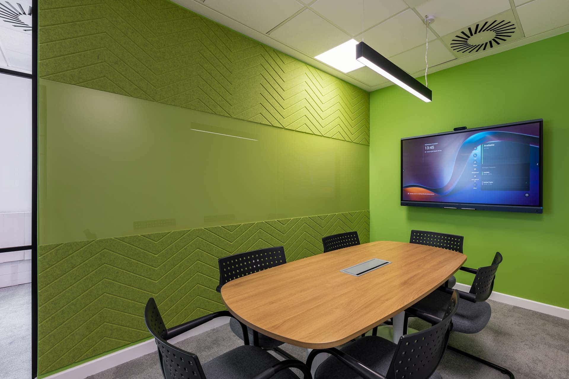 Green board room fit-out with acoustic wall panels, wooden table and office chairs
