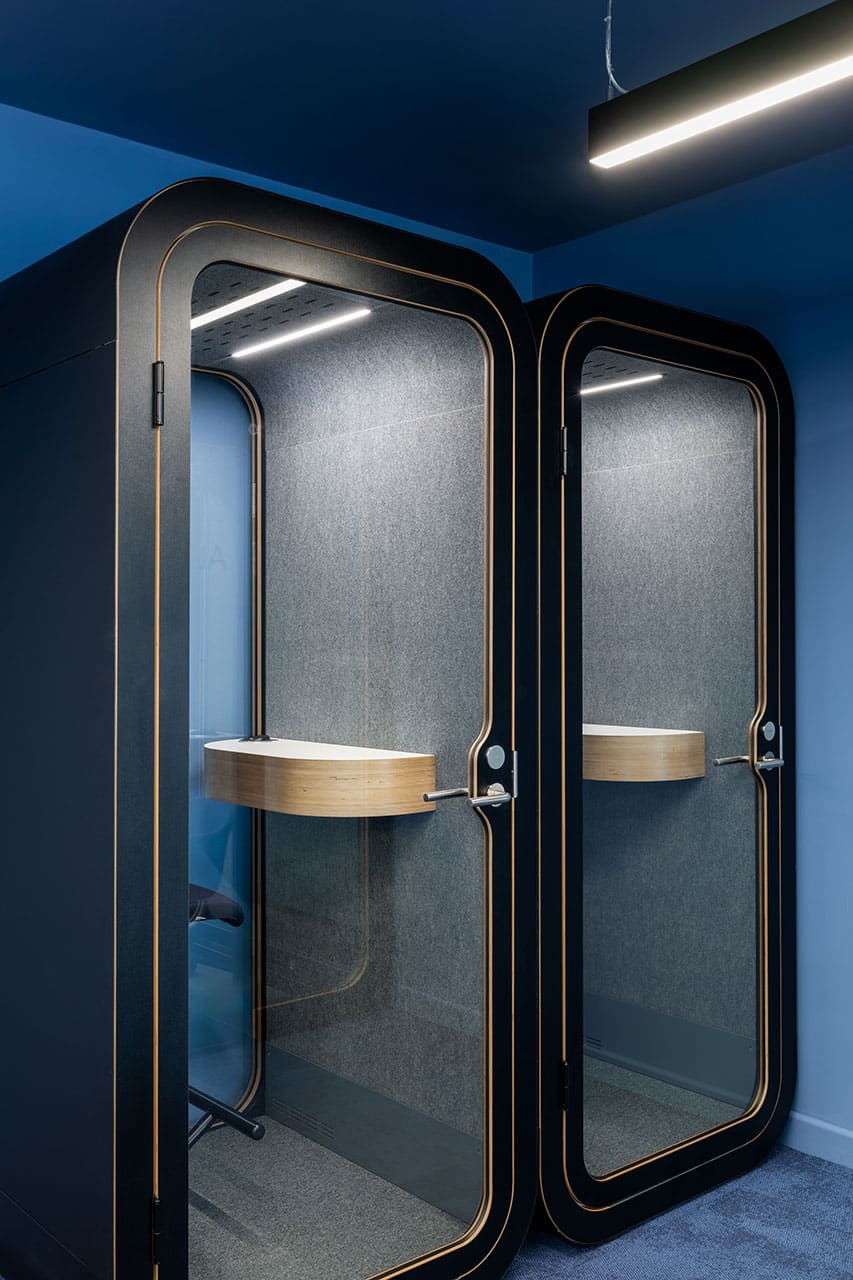 Modern office interior design with quiet meeting pods with integrated desks and acoustic interiors in a blue workspace