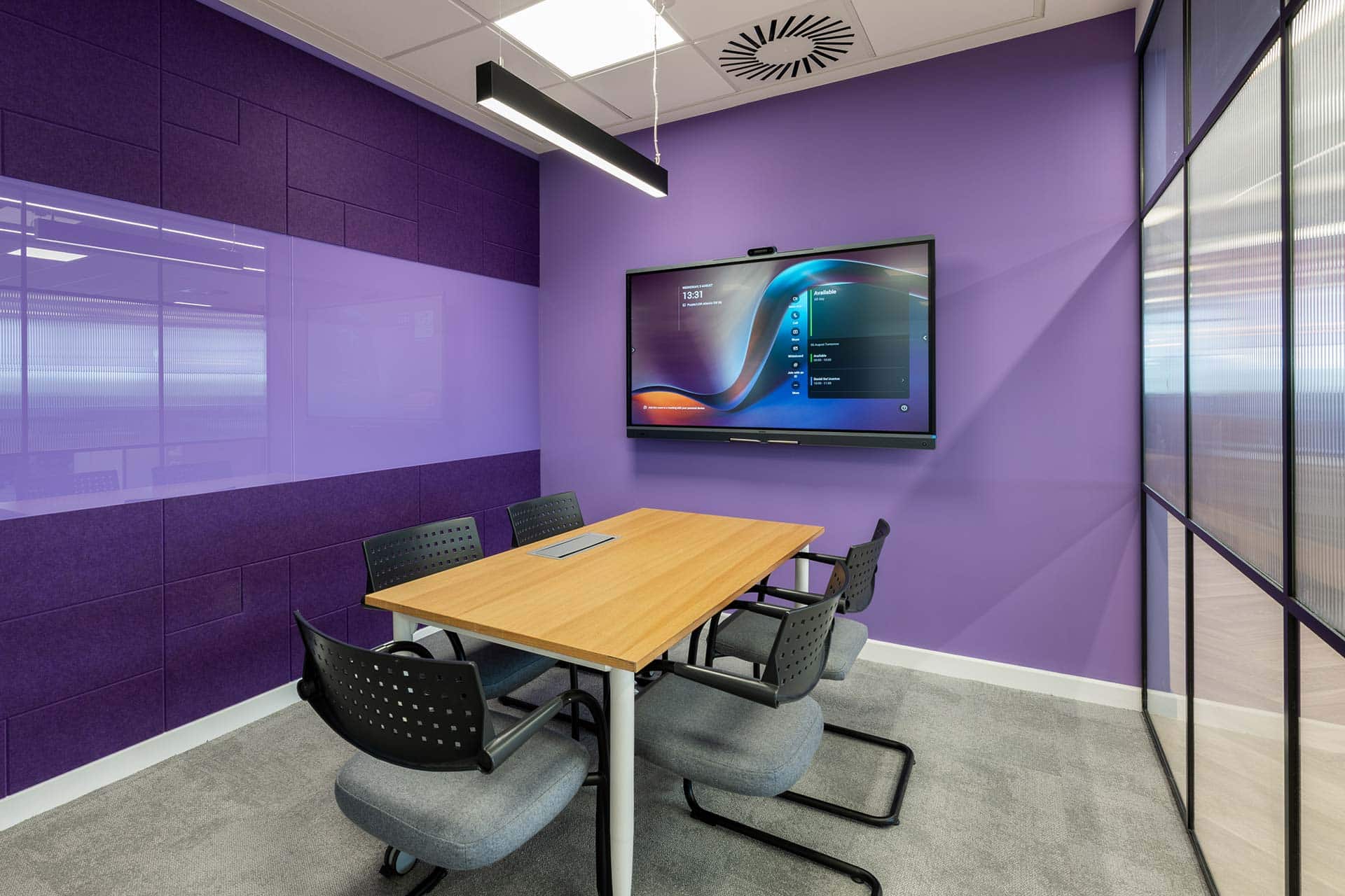 Purple meeting room fit-out with modern conference table, office chairs and video display