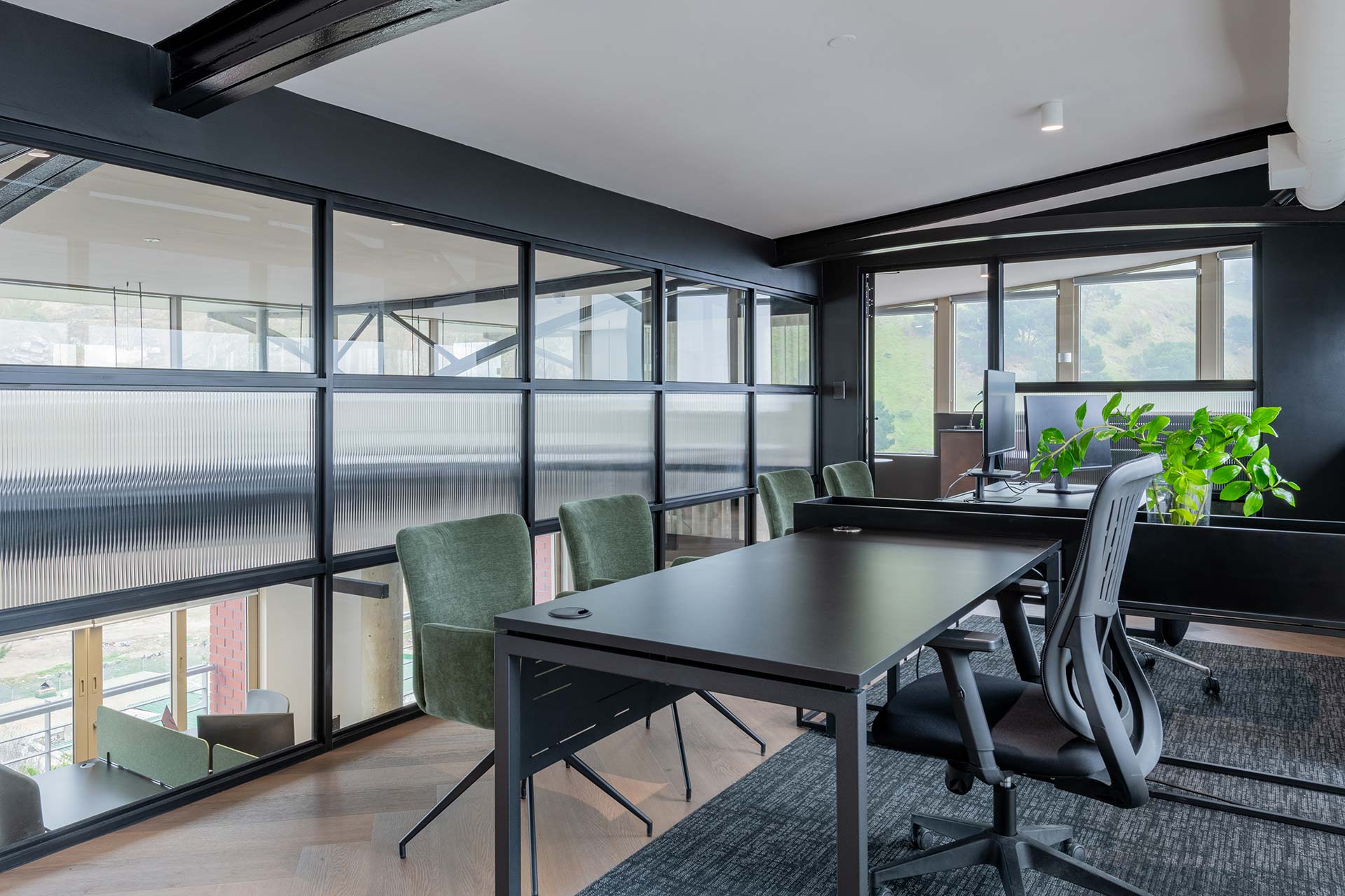 Lionhead Capital modern mezzanine office workspace with black desks, ergonomic chairs and glass partitions