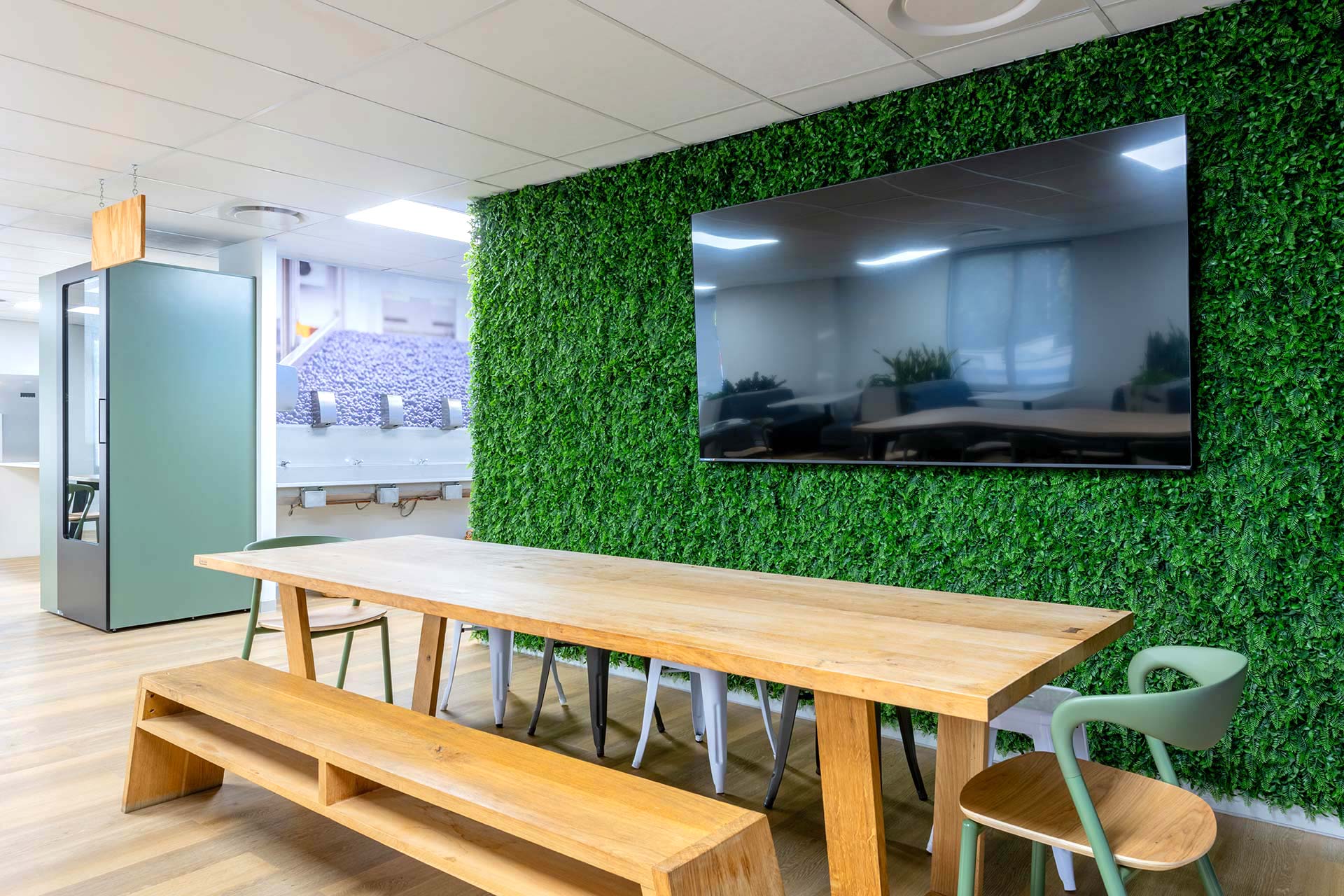 United Exports Paarl office canteen green wall installation design, featuring a modern wooden bench, TV, and green corporate colors.
